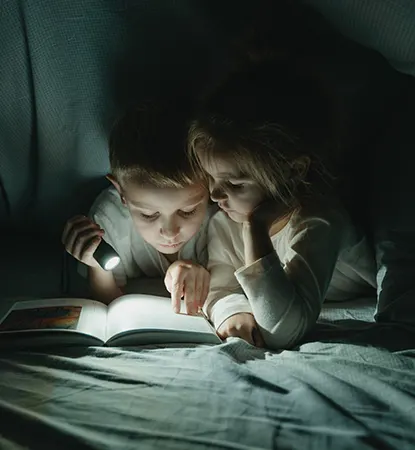 Lesende Kinder mit Taschenlampe